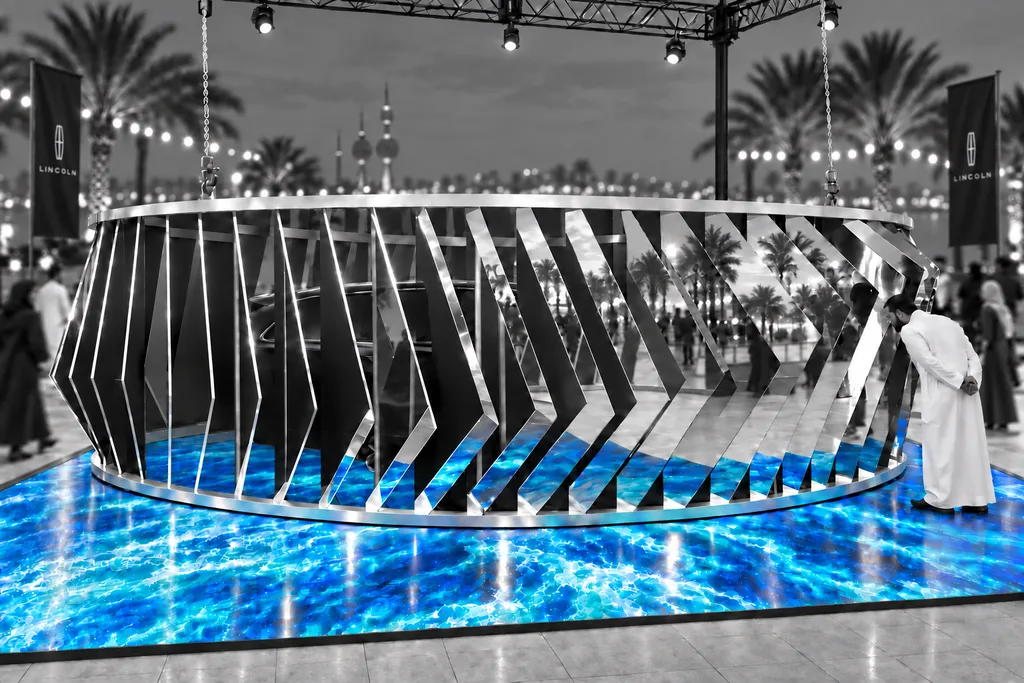 At the Lincoln event in Kuwait, a visitor leans in to look between the mirrored fins at the car hidden inside the ring